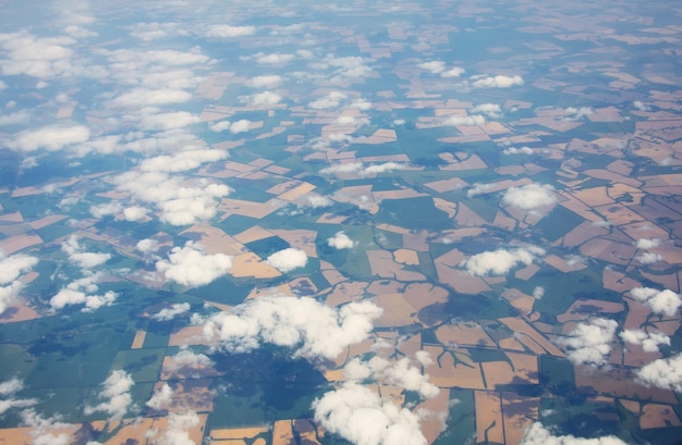 Вид с самолета на возделываемые поля, голубое небо, легкие облака