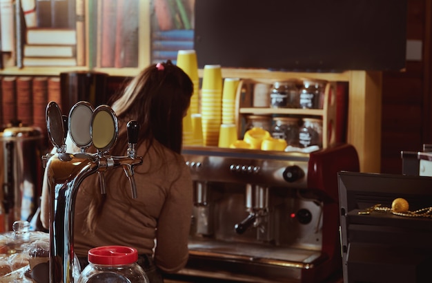 Foto vista dal retro del barista femminile che prepara il caffè nella macchina da caffè professionale