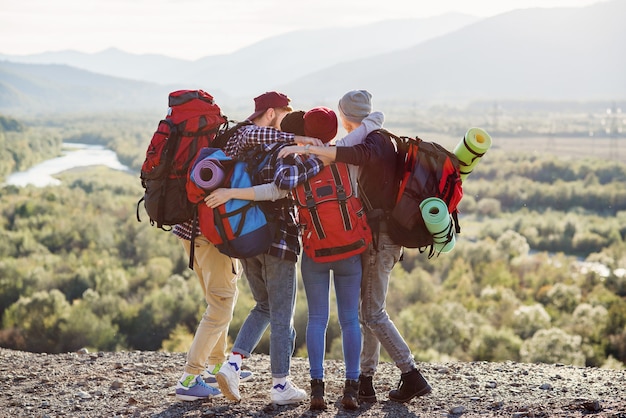 Foto vista dal retro di un viaggiatore di quattro amici hipster, tenendosi per mano in piedi sulla cima della montagna