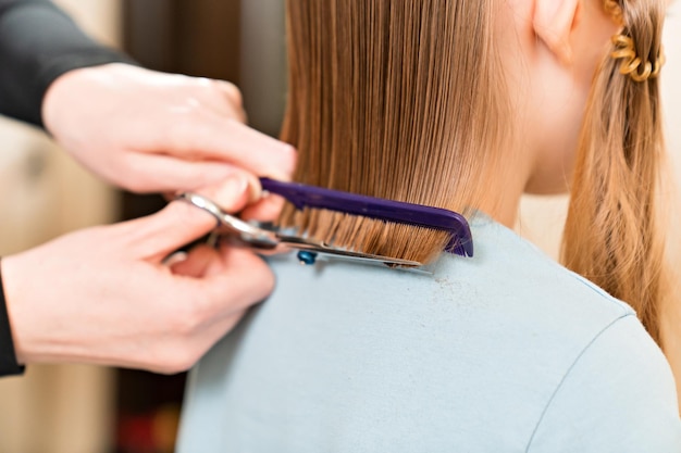 Vista da dietro la mamma taglia i capelli bagnati della figlia tagliando i capelli a casa