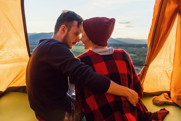 View from back of young man and his girlfriend sitting in a tent