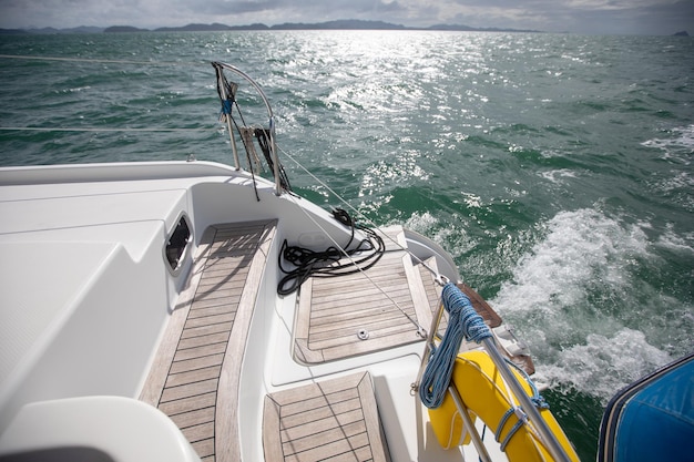 View from board of cutter with blue water and sea foam with a\
boat seen / yachting sport on a summer sunny day with blue sky/\
concept of speed /