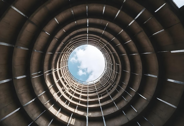 Photo view from the bottom of a cylindrical structure with geometric metal beams leading up to an open