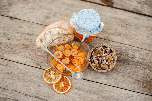 砂糖漬けのオレンジ スパイラル ピールとガラスの瓶に砂糖シロップを入れ、木のテーブルにクルミを置いた受け皿の近くのプレートを上から見た図。