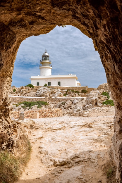 Вид из туннеля Каваллерии на маяк (Faro de Cavalleria). Менорка, Балеарские острова, Испания (вертикальное фото)