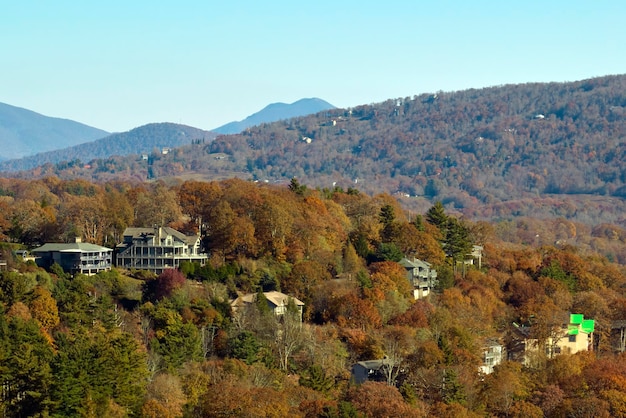 View from above of expensive residential houses high on hill top between yellow fall trees in suburban area in North Carolina American dream homes as example of real estate development in US suburbs