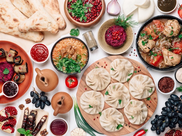 Photo view from above of georgian cuisine on white wooden table traditional georgian cuisine and food khinkali kharcho chahokhbili phali lobio and local sauces tkemali satsebeli adzhika top view