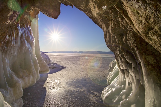 Foto la vista dalla grotta con ghiaccioli, pezzi di ghiaccio e hummocks verso il sole e il cielo blu.