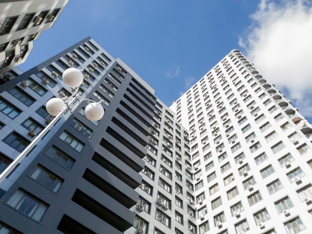 Photo view from the ground on roof tops of modern multistored living building against blue sky and bright sun