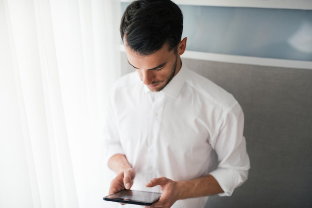 View from above of handsome businessman working with a device gadget in his hands standing in front of a windowBusiness