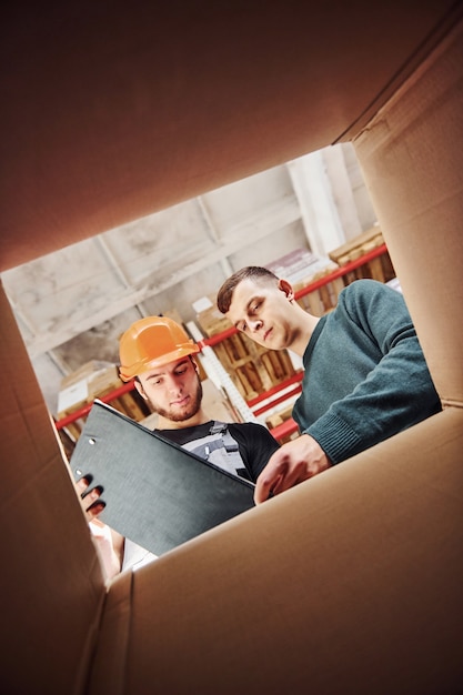 View from inside of the box. Two people with notepad have a work.