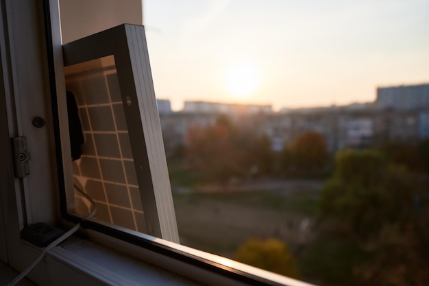 View from inside at solar battery standing on the window of highrise residential building