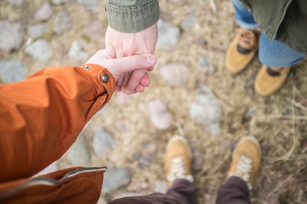 Photo view from above on the legs of a man and a woman standing opposite each other and holding hands