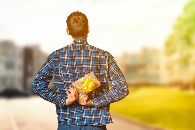 A view from behind man holding a paper gift box to make a surprise on the holiday