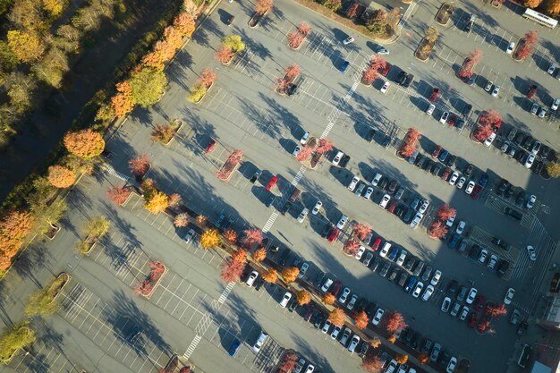 View from above of many parked cars on parking lot with lines and markings for parking places and directions Place for vehicles in front of a strip mall center