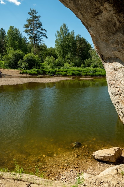 Вид из горной пещеры на речную воду природы Вид на речное озеро и красивый берег с зелеными деревьями