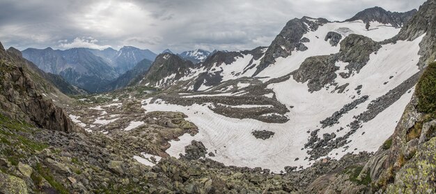 Вид с горного перевала на долину, камни и снег