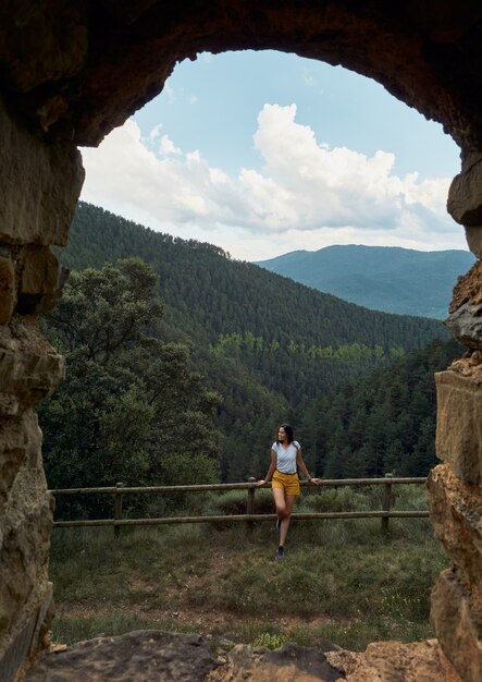 View from a natural window of a female traveler smiling and looking at the mountains