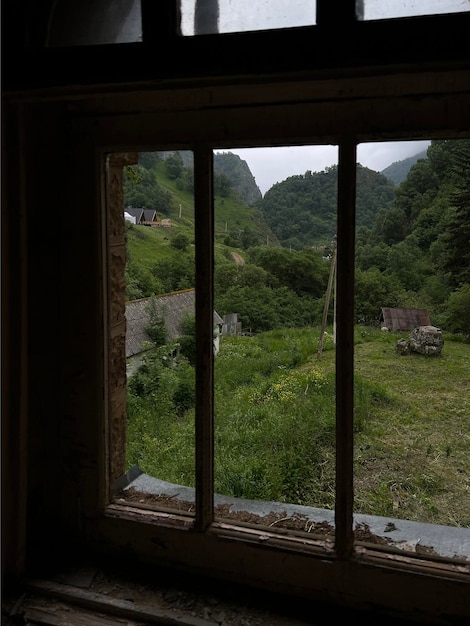 野原と山の緑の中庭の古い窓からの眺め