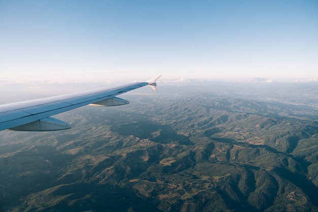 トスカーナの緑豊かな山脈の飛行機の窓からの眺め