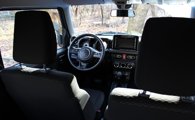 ダッシュボードとフロントパネルの後部座席から 汚れたフロントガラスを持つオフロードカーの内部を眺める