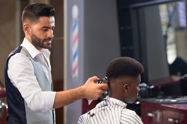 View from side of barber doing trendy haircut in barber shop