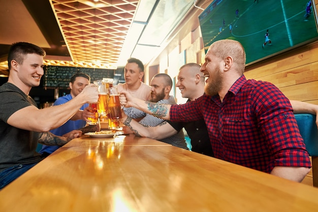View from side of cheerful male company resting together in pub on weekends