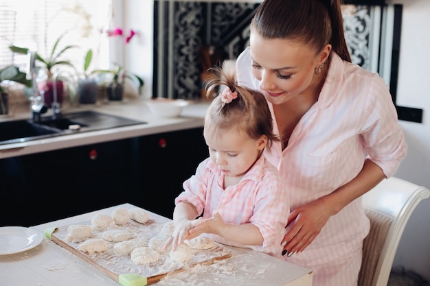 View from side of woman and cute daughter cooking together