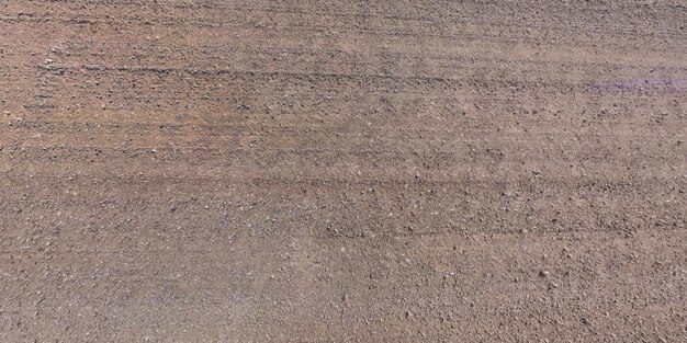 View from above on surface of gravel road with car tire tracks