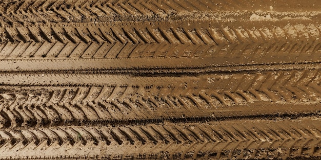 View from above on texture of wet muddy road from above on surface of wet gravel road with tractor tire tracks in countryside