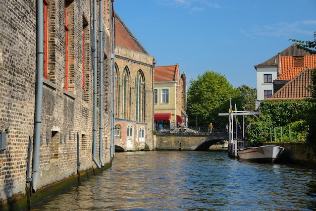 Фото Вид с канала на мостовую лодку и старые кирпичные купеческие дома в брюгге, бельгия древний средневековый вид на город европы
