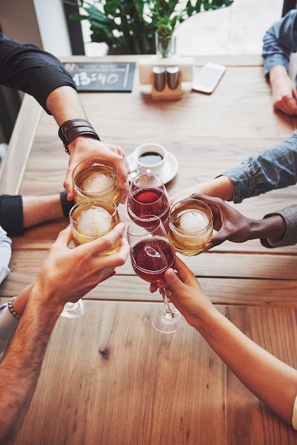 Photo view from the top. hands of people with glasses of whiskey or wine, celebrating and toasting in honor of the wedding or other celebration