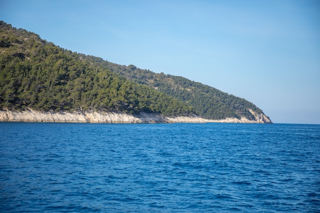 View from water of rocky shore of island in Croatia