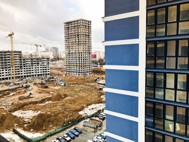 The view from the window from a height of a construction site with cranes and monolithicframe