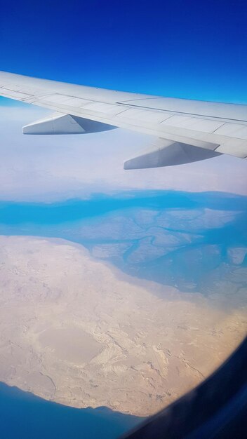 View from the window of plane on blue sky and earth with landscape of desert sea and canals