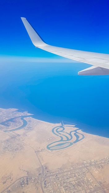 View from the window of plane on blue sky and earth with landscape of desert sea and canals