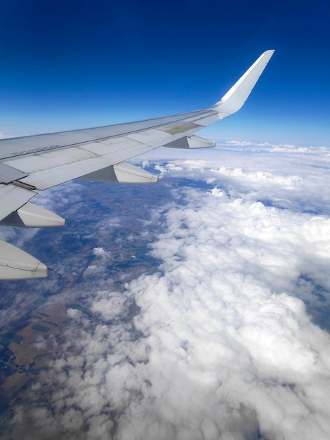 View from the window of the wing of an airplane flying above clouds and a blue sky