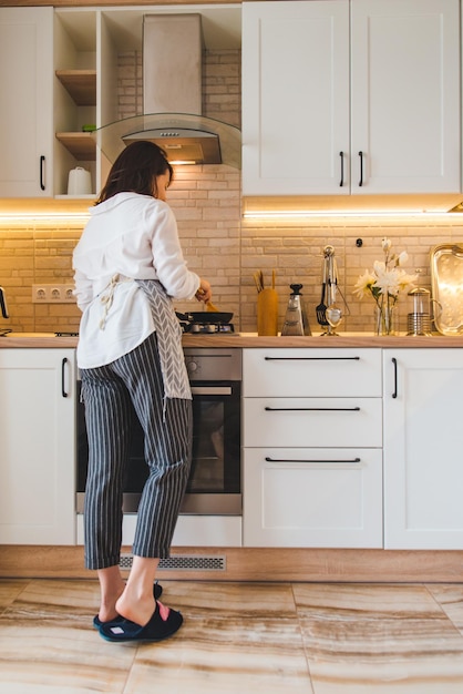 View from behind woman on kitchen cooking