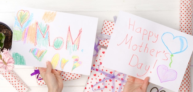 Photo view from above on woman's hands holding handmade greeting cards for mother's day. happy mother's day celebration concept