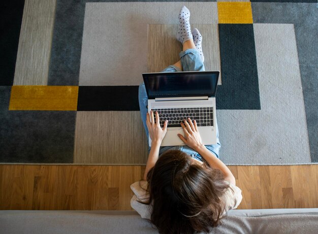 View from above of woman working on a laptop while sitting on the floor A young girl is programming