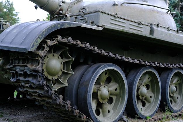 View of the front part of the green caterpillar of the tank standing on the ground with the wheels