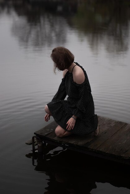 Photo view of a girl in dress near lake in cloudy weather