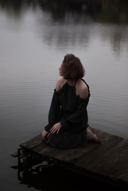 Photo view on a girl in dress near lake in cloudy weather