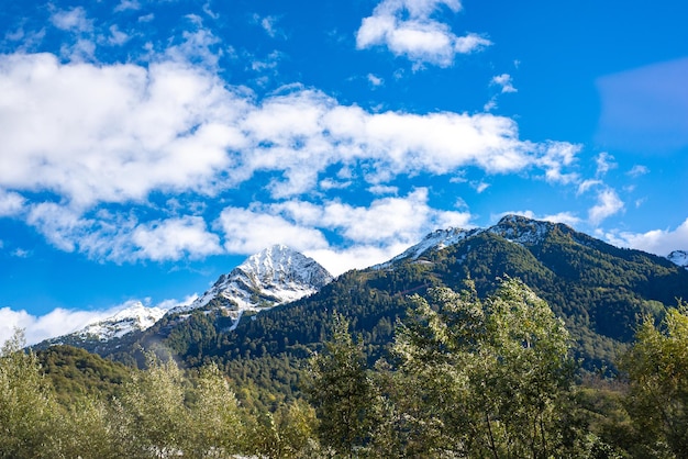 View of the green mountains shrouded in white clouds in sochi against the blue sky