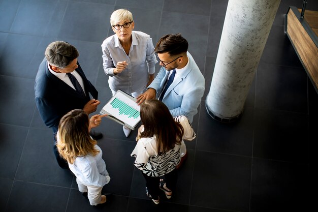 Over view at group of businesspeople standing in the office and analyzing plan