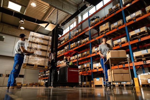 Below view of group of workers preparing shipment in distribution warehouse One of them is using forklift