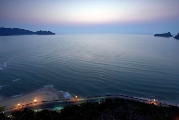 Vista di un golfo con ondulazione blu e una strada lungo la spiaggia in tempo di alba thailandia