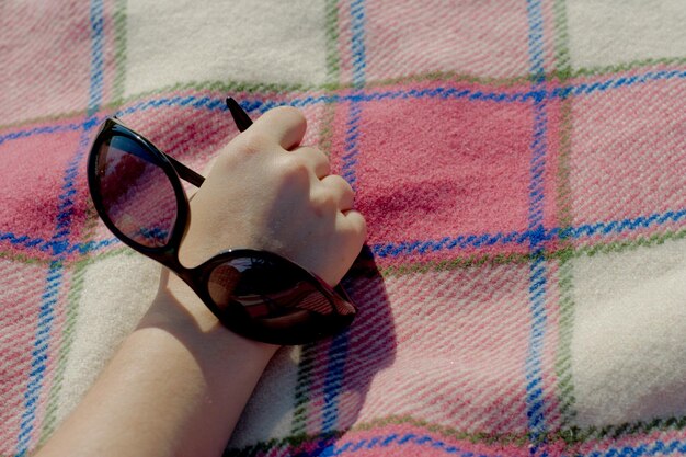 View of hand holding sunglasses