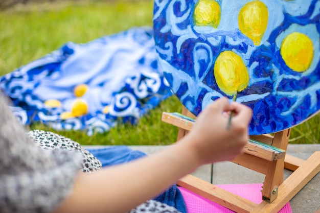 View of hand of young woman painting picture in home terrace