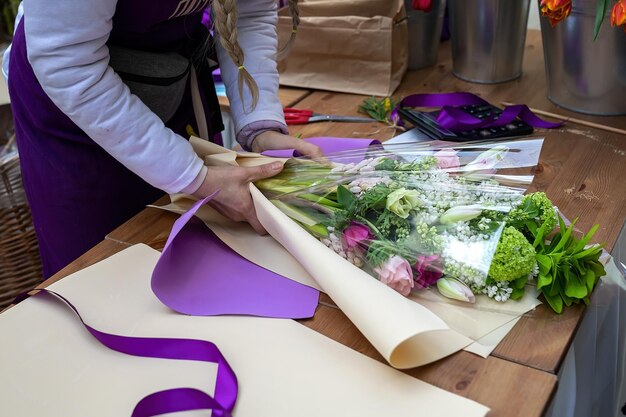 View of hands of girl florist collects a bouquet seller in a flower shop creates a creative bouquet